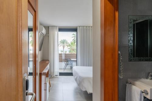 a bedroom with a bed and a bathroom with a window at Hotel Costa Azahar in Grao de Castellón