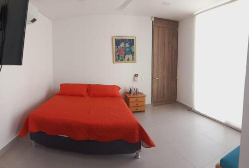 a bedroom with a bed with a red blanket at Casa de Descanso Lili in Ricaurte
