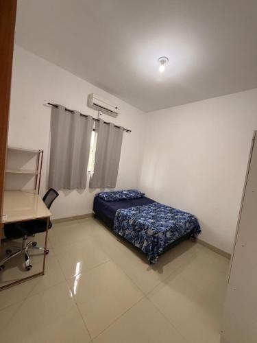 a bedroom with a bed and a desk in it at Casinha Aconchegante in Primavera do Leste