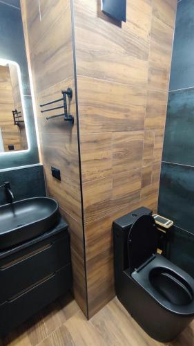 a bathroom with a black toilet and a sink at Centrum apartman s parkovaním in Trenčín