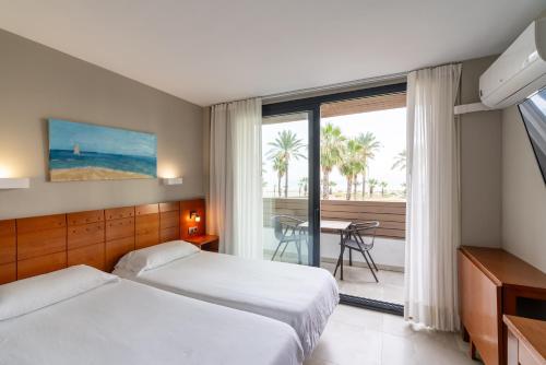 a hotel room with two beds and a view of the ocean at Hotel Costa Azahar in Grao de Castellón