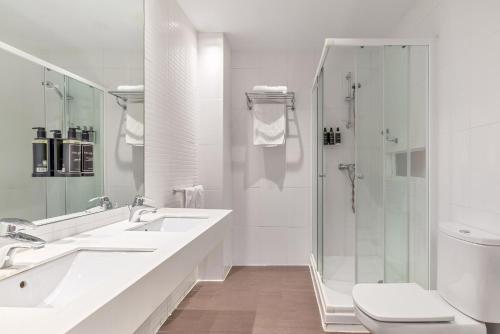 a white bathroom with two sinks and a shower at Dorma Victoria Palace in San Lorenzo de El Escorial