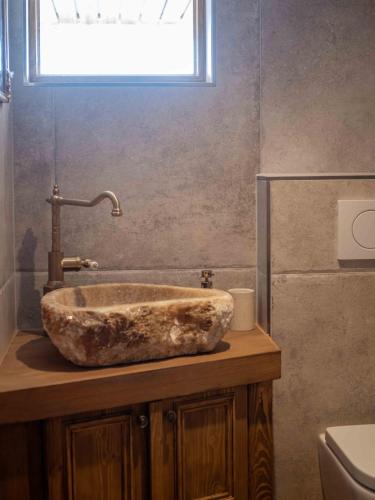 a bathroom with a stone sink with a window at Nido sull`Aqua Chalet with Whirlpool in Sigriswil