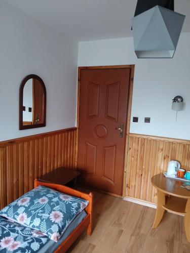 a room with a bed and a door and a table at Na Brzysku in Jabłonka
