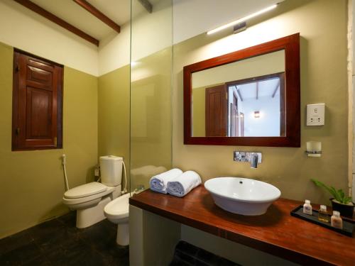 a bathroom with a sink and a toilet and a mirror at Saachi Lagoon Resort in Kalpitiya
