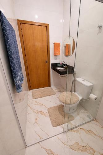 a bathroom with a toilet and a glass shower at Casinha Aconchegante in Primavera do Leste