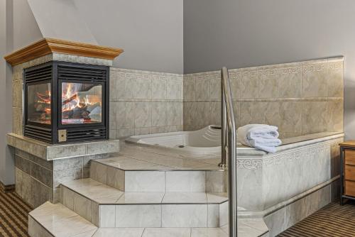 a bathroom with a tub and a fireplace at Canmore Rocky Mountain Inn in Canmore
