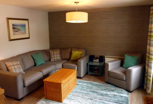 a living room with a couch and two chairs at Holly Tree Cottage in Glencoe