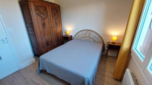 a bedroom with a bed and two lamps on two tables at Gîte 6 pers jardin clos proche plage et lac Cantal in Lacapelle-Viescamp
