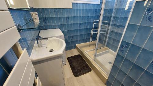 a blue tiled bathroom with a sink and a shower at Gîte 6 pers jardin clos proche plage et lac Cantal in Lacapelle-Viescamp