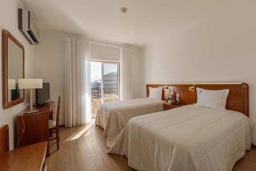 ein Hotelzimmer mit zwei Betten und einem Fenster in der Unterkunft Hotel Comendador in Bombarral