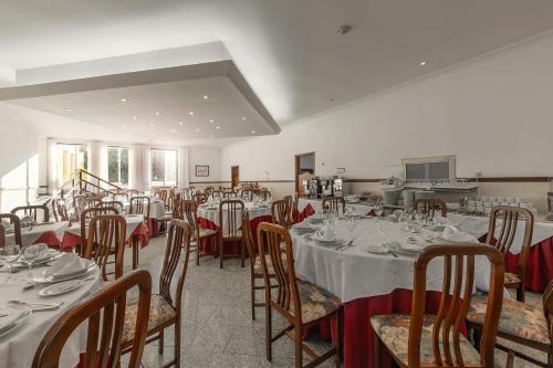 a dining room with white tables and chairs with red bows at Hotel Comendador in Bombarral