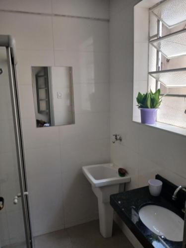 a white bathroom with a sink and a mirror at Aconchego do Lar Centro BH Apto 633 Rua da Bahia 187 in Belo Horizonte