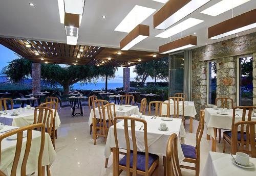a restaurant with white tables and chairs and windows at Eleftheria Hotel in Agia Marina Nea Kydonias