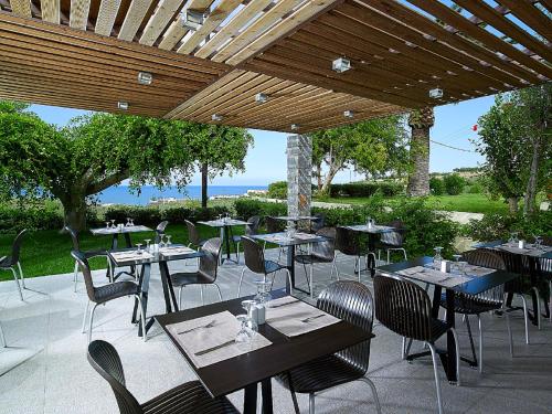 a patio with tables and chairs under a wooden roof at Eleftheria Hotel in Agia Marina Nea Kydonias