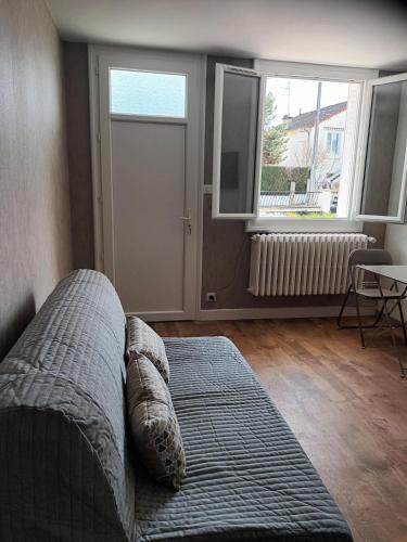 a living room with a bed and two windows at Comfortable studio dans une maison au calme in Bellerive-sur-Allier