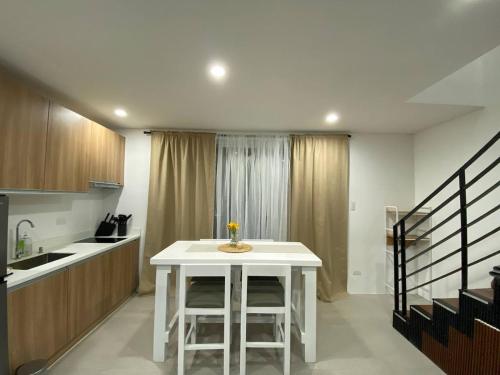 a kitchen with a white table and some stairs at Cozy Haven Batulao in Calo