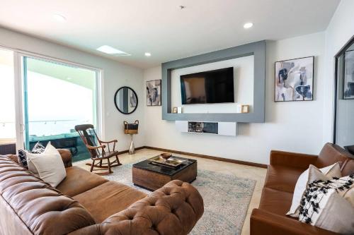 a living room with a couch and a tv at Mar y Sol 16th floor Condo in Rosarito