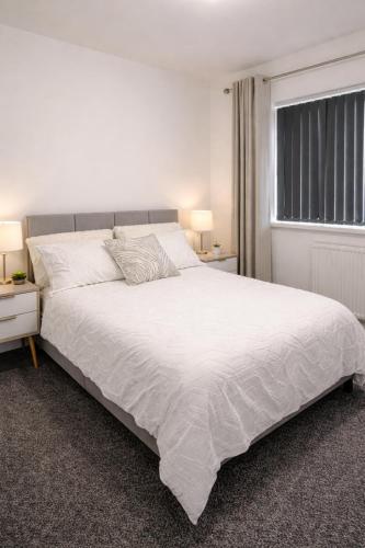 a bedroom with a large white bed with two night stands at Spacious 2 bedoom house in Wyken