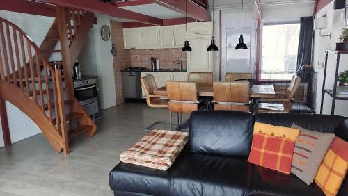 a living room with a black leather couch and a table at Vakantiehuis Toermalijn in Simpelveld