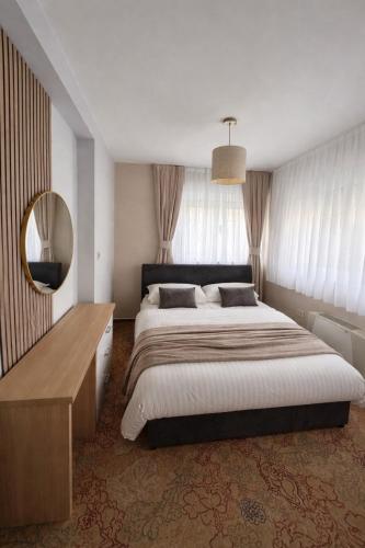 a bedroom with a large bed and a mirror at Villa AYA - with sauna and outdoor swimming pool in Mostar
