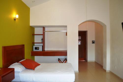 a bedroom with a bed and a yellow wall at Concierge Plaza La Villa in Colima