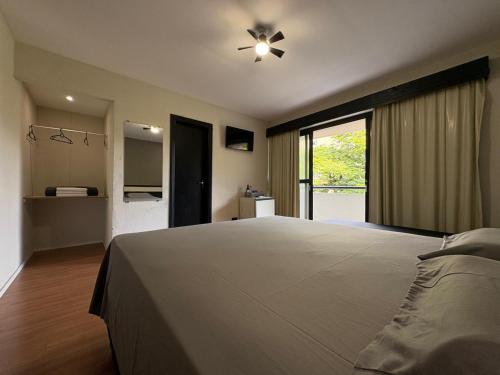 a bedroom with a large bed and a large window at Travessa 12 - Suítes centro de Serra Negra - SP in Serra Negra