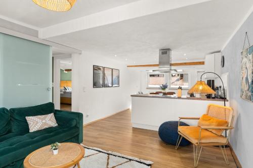 a living room with a green couch and a kitchen at Tucan - Rooftop Terrace with View, BBQ, PS4+Stream in Marburg an der Lahn
