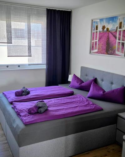 a bedroom with two beds with purple sheets and purple pillows at Penthouse Seebrise in Großräschen