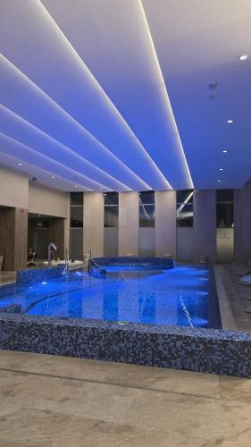 a large pool with blue water in a building at 4 Sosny Porta Mare in Dziwnówek