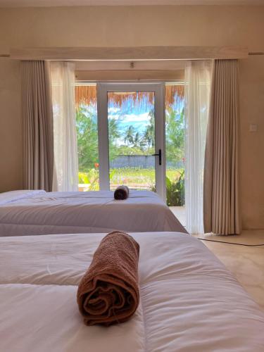 a bedroom with two beds and a window with a towel at Daumi House in Masbagik