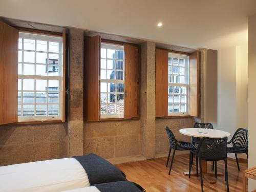 een kamer met een bed, een tafel en ramen bij Belomont6 Apartments in Porto