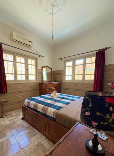 a bedroom with a bed and a table and windows at Villa Palm Desert- your Private Stay with AC, Fast WiFi & Parking in Erfoud