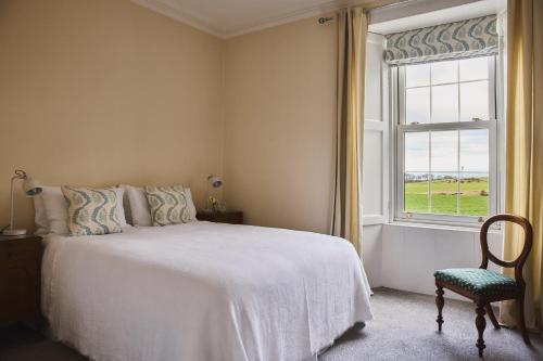 a bedroom with a bed with a window and a chair at Banchory Farm in Fife