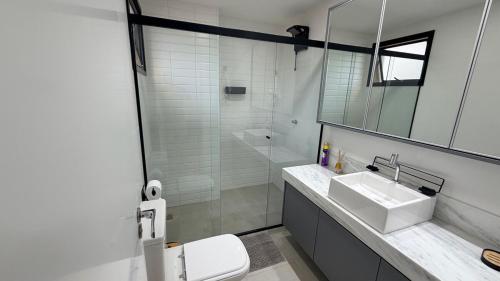 a white bathroom with a sink and a shower at Royal ID Setor Oeste in Goiânia