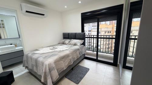a bedroom with a bed and a sink and windows at Royal ID Setor Oeste in Goiânia