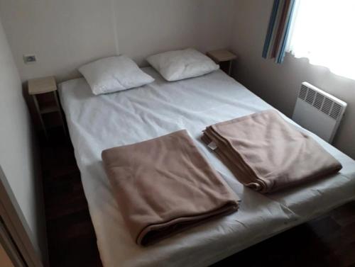 a bed with two pillows and a bag on it at Camping 3 étoiles - ccbfgdc in Neuvic