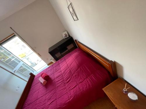 a small bedroom with a red bed and a window at Casa Verde in Braga