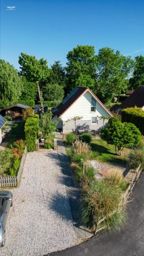 a house with a gravel driveway in a yard at "ZeeLandZon" Holiday home by the lake with Jacuzzi and Sauna in Herkingen