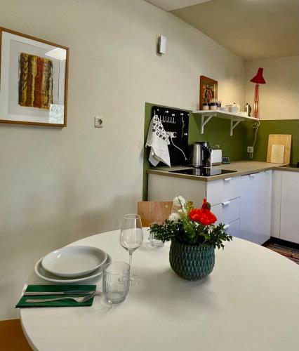 a table with glasses and a vase of flowers on it at Studio Auenland in Kottingbrunn