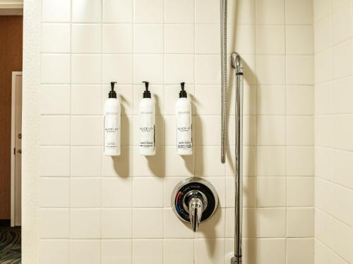 a shower with three bottles on the wall at The Beacon Charlotte Airport by IHG in Charlotte