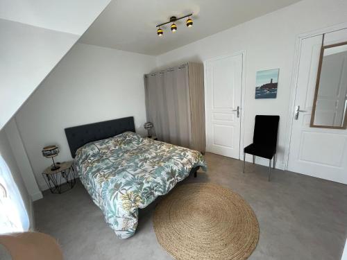 a bedroom with a large bed and a chair at Centre Treguier L escapade des quais in Tréguier