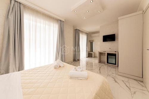 a white bedroom with a large bed with towels on it at Riviera Luxury Rooms in Porto Cesareo