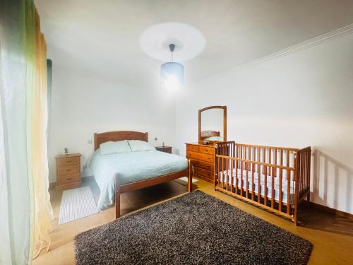 a bedroom with a bed and a mirror and a crib at Cantinho da Paz in Marinhas