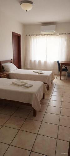 a row of beds in a room with a window at Fazio Hotel in Jales