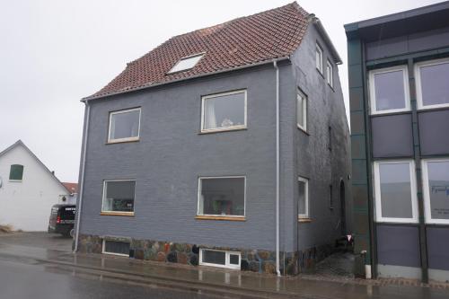 a gray house with a red roof on a street at Værelse tæt på strand og by in Hirtshals