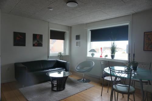 a living room with a couch and a table at Værelse tæt på strand og by in Hirtshals
