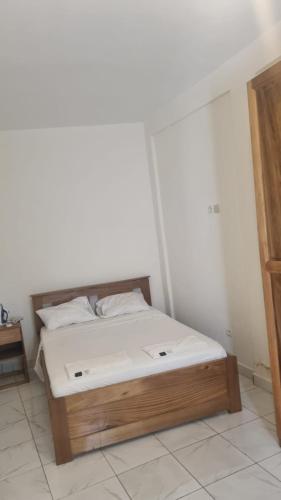 a bed with a wooden frame in a room at RESIDENCE Tanta in Douala