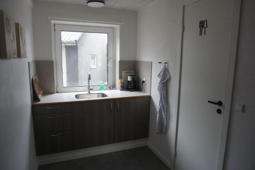 a bathroom with a sink and a window at Værelse tæt på strand og by in Hirtshals