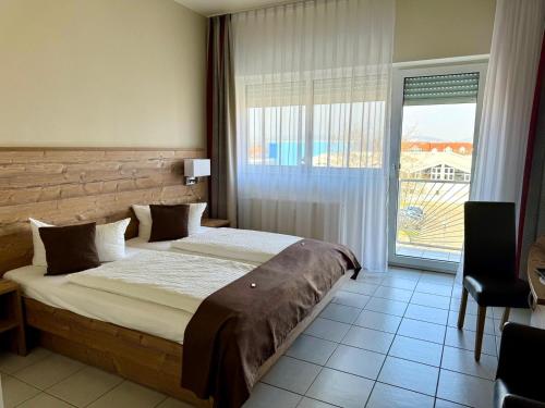 a bedroom with a large bed and a large window at Hotel Nahetal in Gensingen